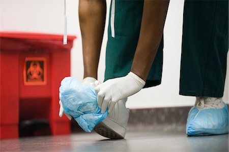 disposable - Healthcare worker putting on disposable shoe covers Stock Photo - Premium Royalty-Free, Code: 632-03651972