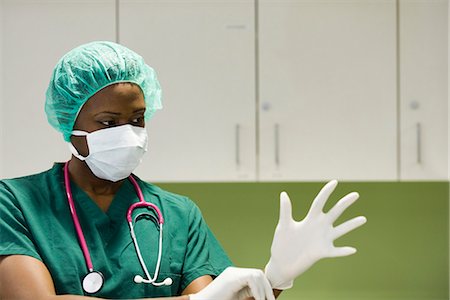 Nurse wearing surgical mask putting on latex gloves Stock Photo - Premium Royalty-Free, Code: 632-03651986