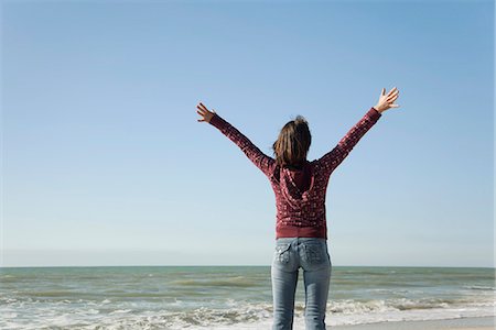 simsearch:632-03652079,k - Woman standing on beach with arms raised Fotografie stock - Premium Royalty-Free, Codice: 632-03652054