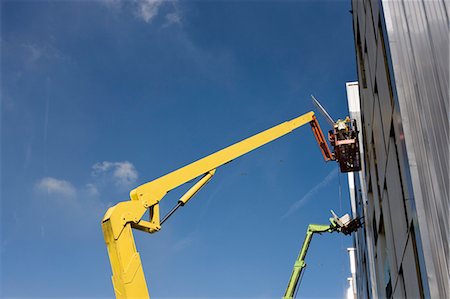 simsearch:632-01784566,k - Construction workers in cherry picker bucket working on building exterior Fotografie stock - Premium Royalty-Free, Codice: 632-03652219