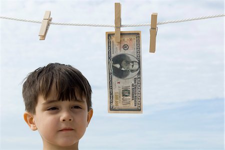 Boy contemplating one million dollar bill hanging on clothes-line Stock Photo - Premium Royalty-Free, Code: 632-03652289