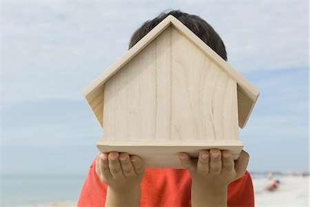 Boy holding wooden birdhouse in front of face Stock Photo - Premium Royalty-Free, Code: 632-03652291