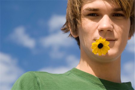 Young man with flower in mouth, portrait Stock Photo - Premium Royalty-Free, Code: 632-03652324
