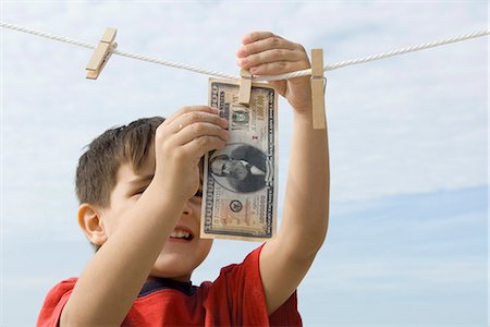 Boy hanging one million dollar bill on clothes-line Foto de stock - Sin royalties Premium, Código: 632-03652330