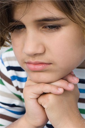 Boy with hands clasped under chin, looking down, portrait Stock Photo - Premium Royalty-Free, Code: 632-03652332