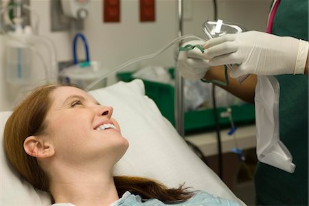 simsearch:632-03754377,k - Female patient smiling as nurse prepares oxygen mask Foto de stock - Royalty Free Premium, Número: 632-03754341