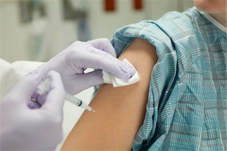 Doctor placing gauze on patient's arm after administering a shot Stock Photo - Premium Royalty-Free, Code: 632-03754420