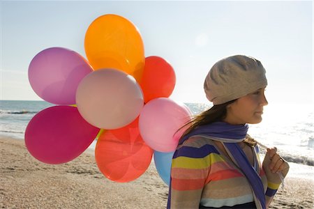 Preteen girl with bunch of balloons walking on beach Foto de stock - Sin royalties Premium, Código: 632-03754438