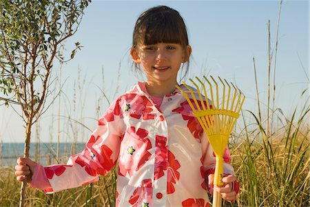 simsearch:632-05759978,k - Young girl with gardening rake standing next to tree sapling Stock Photo - Premium Royalty-Free, Code: 632-03754509