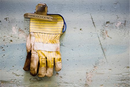 Protective work gloves held up by a binder clip on wall Fotografie stock - Premium Royalty-Free, Codice: 632-03754524