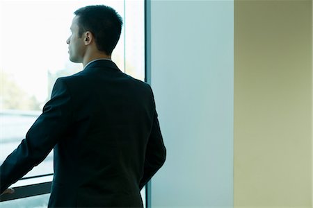 Young businessman looking out window in thought Stock Photo - Premium Royalty-Free, Code: 632-03779547