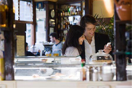 Couple looking at cell phone together in cafe Stock Photo - Premium Royalty-Free, Code: 632-03779639