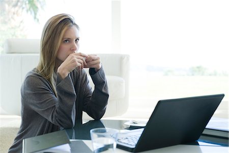 simsearch:632-03847818,k - Woman sitting at coffee table with laptop computer, drinking coffee Stock Photo - Premium Royalty-Free, Code: 632-03847789