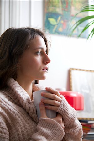 Young woman holding coffee cup, looking away in thought Stock Photo - Premium Royalty-Free, Code: 632-03848015