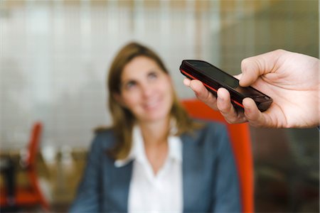 Person using cell phone, female executive in background Stock Photo - Premium Royalty-Free, Code: 632-03848054