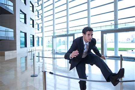 Businessman jumping over rope in lobby Foto de stock - Sin royalties Premium, Código: 632-03848099