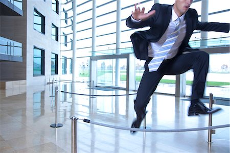 Businessman jumping over ropes in lobby Stock Photo - Premium Royalty-Free, Code: 632-03848103