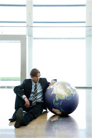 people with globe - Businessman sitting next to ball in lobby Stock Photo - Premium Royalty-Free, Code: 632-03848124