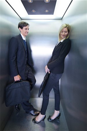 smiling businessman in elevator - Colleagues playing footsies in elevator Stock Photo - Premium Royalty-Free, Code: 632-03848123