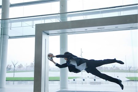 Businessman catching soccer ball in lobby Stock Photo - Premium Royalty-Free, Code: 632-03848134