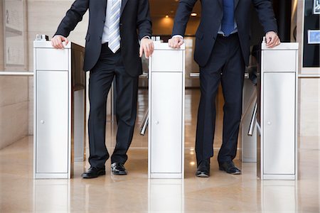 Businessmen walking through turnstiles, cropped Fotografie stock - Premium Royalty-Free, Codice: 632-03848144
