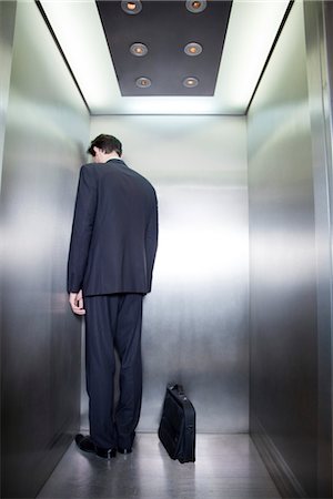 final de la línea - Businessman standing in corner of elevator with back to camera and head down Foto de stock - Sin royalties Premium, Código: 632-03848145