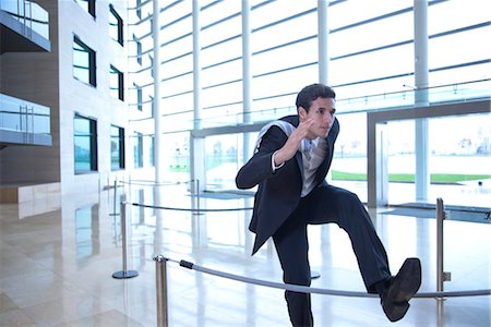 simsearch:632-03779793,k - Businessman jumping over rope in lobby Foto de stock - Royalty Free Premium, Número: 632-03848155