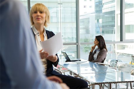 Businesswoman looking away in thought, colleagues in foreground Foto de stock - Royalty Free Premium, Número: 632-03848216