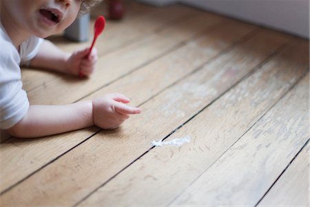 spill accident - Toddler lying on floor with spoon in hand, pointing to spilled food Stock Photo - Premium Royalty-Free, Code: 632-03848234