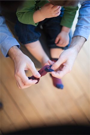 parent holding child hand - Father helping toddler put on socks, cropped Stock Photo - Premium Royalty-Free, Code: 632-03848238