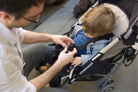 simsearch:632-03848389,k - Father strapping toddler boy into stroller Foto de stock - Royalty Free Premium, Número: 632-03848252