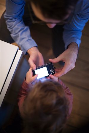 simsearch:632-03848230,k - Father and young son looking at digital camera together, overhead view Stock Photo - Premium Royalty-Free, Code: 632-03848281