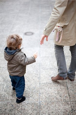 dad son hold hand walk back - Father reaching for toddler's hand on sidewalk, cropped Stock Photo - Premium Royalty-Free, Code: 632-03848324