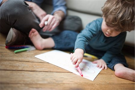 Toddler boy sitting on floor with parent, drawing on paper Foto de stock - Sin royalties Premium, Código: 632-03848423