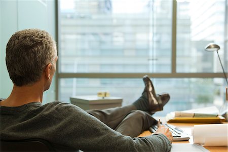 Executive sitting in office with feet on desk, rear view Foto de stock - Sin royalties Premium, Código: 632-03897791