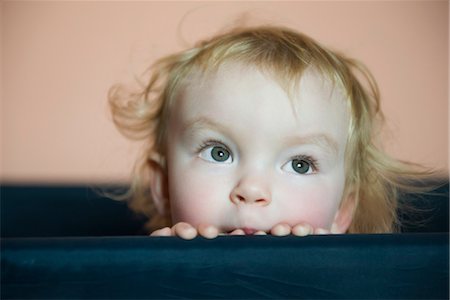 Baby girl peering over side of crib, portrait Stock Photo - Premium Royalty-Free, Code: 632-03897808
