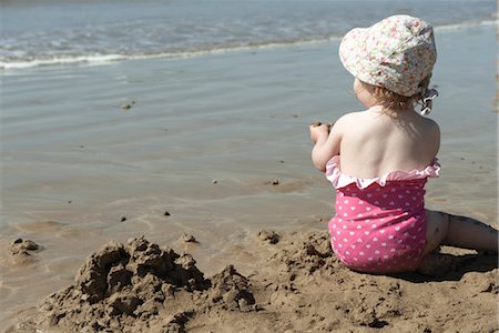 Fille enfant en bas âge jouer dans le sable à la plage, vue arrière Photographie de stock - Premium Libres de Droits, Code: 632-03897877