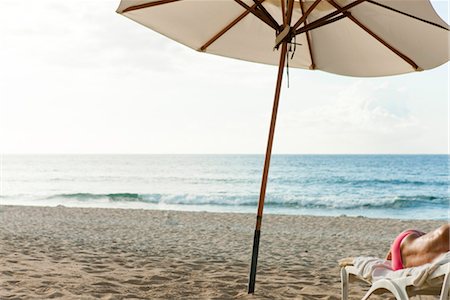 parasol - Beach umbrella on beach, semi-naked person lying on deckchair Foto de stock - Sin royalties Premium, Código: 632-03897871