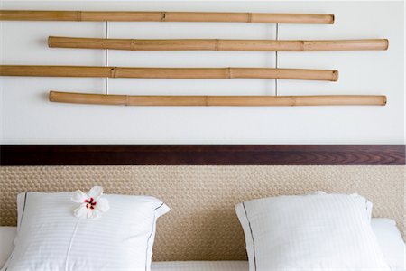 Bamboo decoration hanging on wall above headboard, white hibiscus flower head on pillow Stock Photo - Premium Royalty-Free, Code: 632-03898030