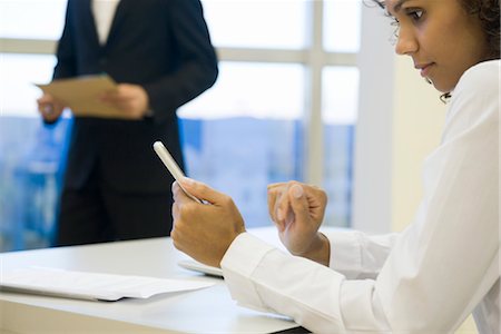 smartphone on desk - Businesswoman looking at cell phone Stock Photo - Premium Royalty-Free, Code: 632-03898339