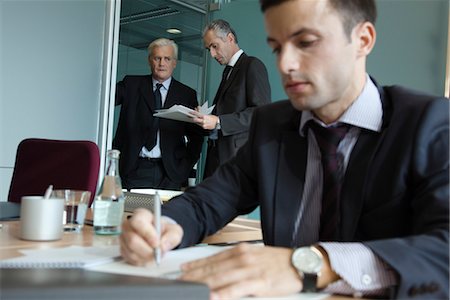 simsearch:632-05553837,k - Executives in discussion, young businessman working in foreground Stock Photo - Premium Royalty-Free, Code: 632-03898444