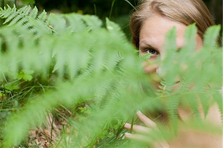 simsearch:633-06406668,k - Woman peeking through fern frond, portrait Stock Photo - Premium Royalty-Free, Code: 633-05401418