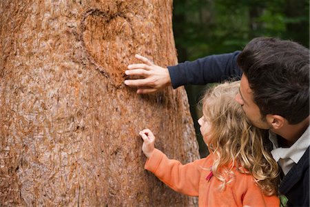 Father and young daughter touching tree trunk Stock Photo - Premium Royalty-Free, Code: 633-05401449