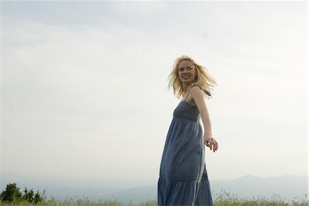 simsearch:633-05402126,k - Young woman standing in meadow on breezy day, bubbles floating around her Stock Photo - Premium Royalty-Free, Code: 633-05401546