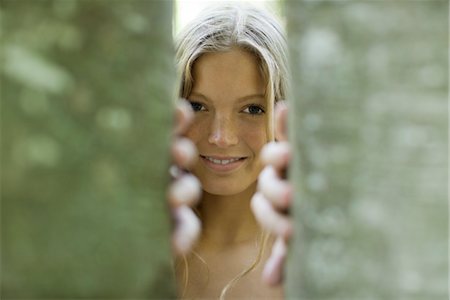 dietro - Young woman peering out from behind tree trunks Fotografie stock - Premium Royalty-Free, Codice: 633-05401574