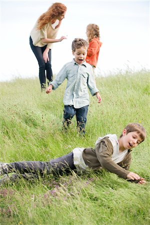 family playing in the grass - Boys playing in field, mother and sister in background Stock Photo - Premium Royalty-Free, Code: 633-05401576