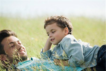 father son lying grass - Father and young son lying down together in grass Foto de stock - Sin royalties Premium, Código: 633-05401618