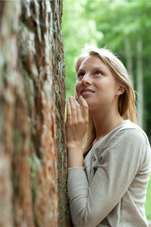 sonrisa sardónica - Woman leaning against tree, looking up Foto de stock - Sin royalties Premium, Código: 633-05401658