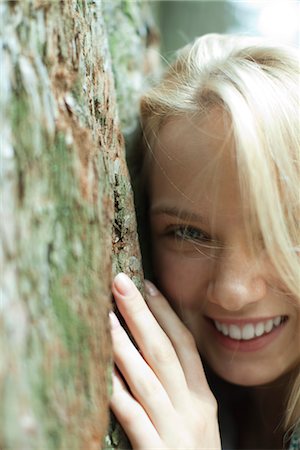 simsearch:633-05401416,k - Smiling young woman leaning against tree trunk, cropped Stock Photo - Premium Royalty-Free, Code: 633-05401736
