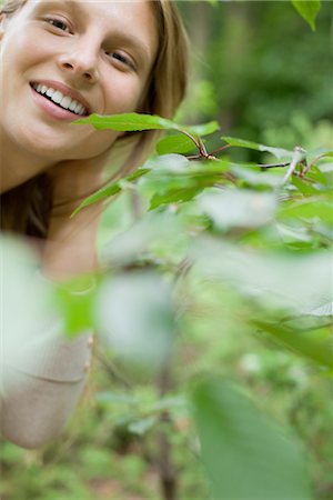 simsearch:633-06406668,k - Woman smiling at camera from behind foliage, portrait Stock Photo - Premium Royalty-Free, Code: 633-05401783